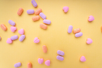 Top view - Pastel colourful vitamin medicine over bright yellow background. Messy and seperate.