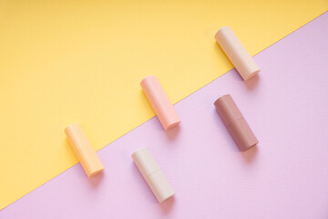 Commercial product - Group of pastel beige lipsticks on yellow and purple background.