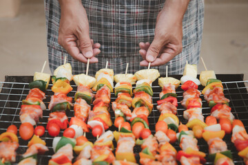 A man grilling pork and barbecue in dinner party. Food, people and family time concept.
