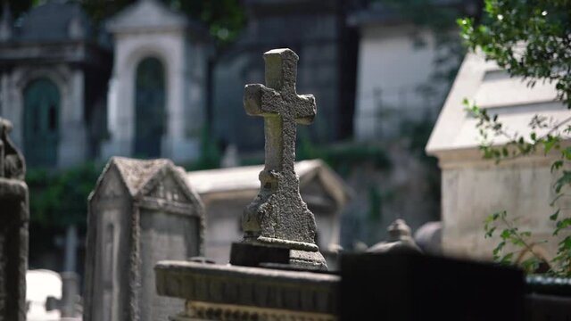Christian stone cross in a cementry outdoors with tombstones on background