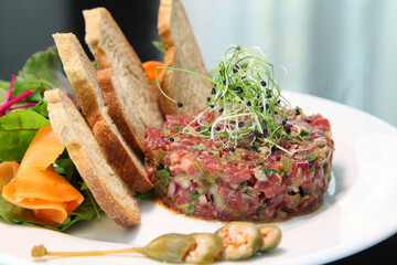 Raw tartar meat with spices, croutons and herbs. Beef tartar with capers. Beef tartar with slices of bread.  Raw meat tartare for gourmet meat.