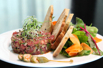 Raw tartar meat with spices, croutons and herbs. Beef tartar with capers. Beef tartar with slices of bread.  Raw meat tartare for gourmet meat.