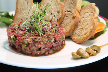 Raw tartar meat with spices, croutons and herbs. Beef tartar with capers. Beef tartar with slices of bread.  Raw meat tartare for gourmet meat.