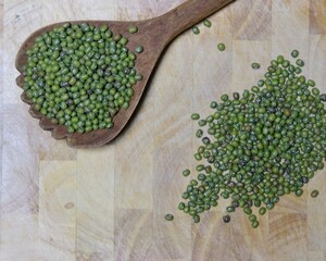 Green peas piled on an old wooden ladle.