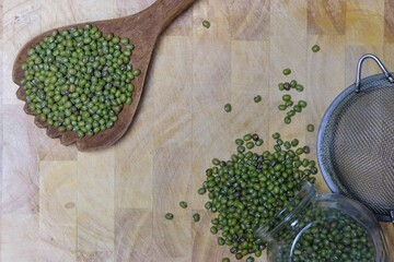 Green peas piled on an old wooden ladle.