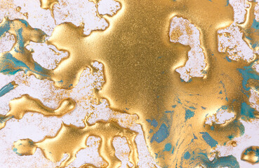 Golden ink drops on white paper background.
