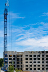 Fototapeta premium A crane over a house under construction against the blue sky