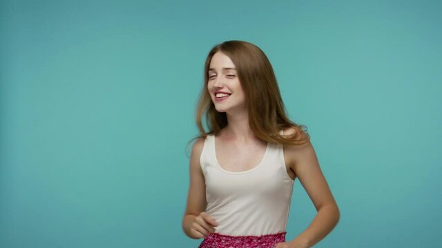Amazing beautiful playful girl moving in dance, smiling carefree and stops in dab dance pose, performing dabbing trends, gesture of success, internet meme. studio shot isolated on blue background