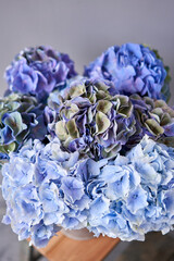 Beautiful blue hydrangea flowers in a vase on a table . Bouquet of light pink flower. Decoration of home. Wallpaper and background.