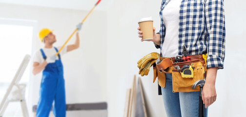 repair, construction and building concept - woman or builder with takeaway coffee cup and working tools on belt over painter painting ceiling background