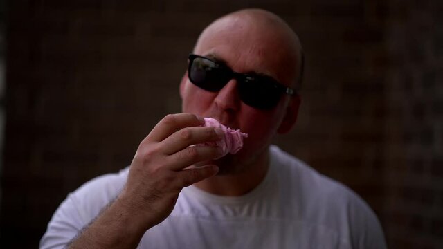 sweet tooth adult man is eating pink sweety cake, enjoying cookies, unhealthy nutrition