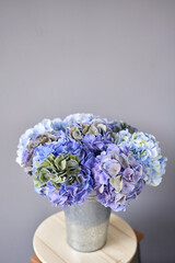 Beautiful blue hydrangea flowers in a vase on a table . Bouquet of light pink flower. Decoration of home. Wallpaper and background.