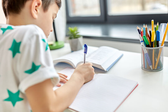 education, school and people concept - close up of boy writing to notebook at home