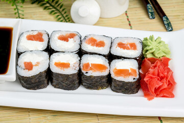 Sushi on a white plate with sauce and seasonings