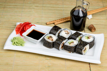 Sushi on a white plate with sauce and seasonings