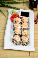 Sushi on a white plate with sauce and seasonings