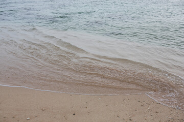 natural filled frame close up background wallpaper shot of an ocean wave on the smooth yellow sand beach surface. Pitiwella beach, Sri Lanka
