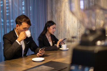 Business men and women drink coffee and use mobile phones in coffee shops in the evening