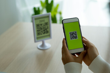 The woman's hand is using the phone to scan the qr code to select the food menu. Scan to receive discounts or pay for food and to use to transfer money online without cash in restaurant or cafe.