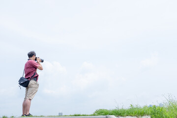 河川敷で空の写真を撮影する男性