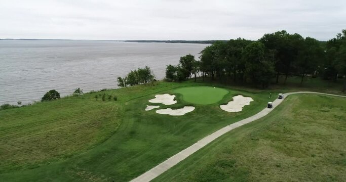 Flying over the green grass rough on a golf course next to a large lake in Maryland
