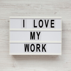 'I love my work' on a lightbox on a white wooden surface, top view. Flat lay, from above, overhead.