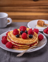 Sweet homemade pancakes with raspberries and blueberries on white plate.