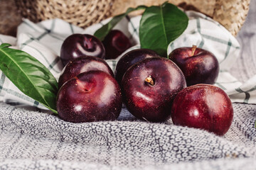 purple plums in striped cloth, placed in a wicker basket