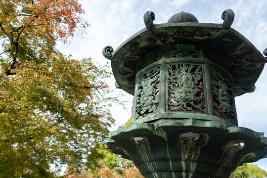 Traditional stone carved japanese lantern (Toro) in Ninna-ji  Temple Complex park in Kyoto, Japan, during autumn, with colorful autumn leaves.