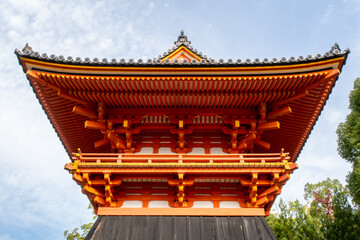 Naklejka premium Symmetrical front view of traditional orange wooden Syoro Pagoda with carved roof in Ninna-ij Temple in Kyoto, Japan, with blue sky in the background, autumn.