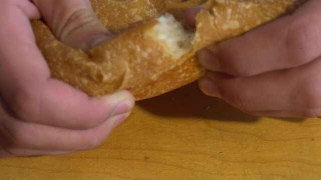 Caucasian man baker breaks Georgian pita into two parts. Close-up macro of a breaking bread.