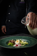 Top view of traditional Russian summer kefir or yogurt cold soup with vegetables called Okroshka. on a dark background