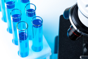 Close up of laboratory microscope with set of test tubes with blue liquid