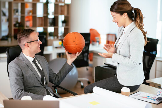 Businesswoman and businessman with basketball in office. Young man and woman having fun at work.	