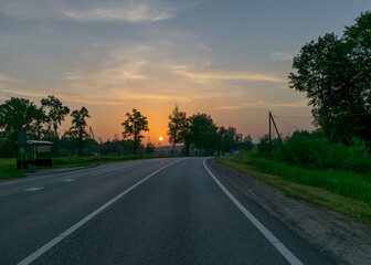 Fototapeta premium sunrise landscape, dark tree silhouettes, paved road texture, contrasting colors, summer