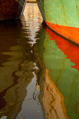 Dual reflections of colorful ship hulls in the waters of Sunda Kelapa Harbour of Jakarta, Indonesia.