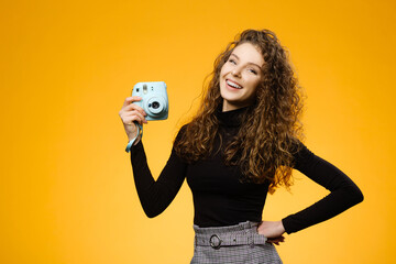 Beautiful girl with photo camera isolated on yellow background