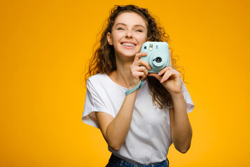 Fototapeta premium Beautiful girl with camera isolated on yellow background