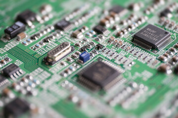 Obraz premium Fragment elektronicznej płytki drukowanej z wieloma komponentami elektrycznymi o małej głębi ostrości.