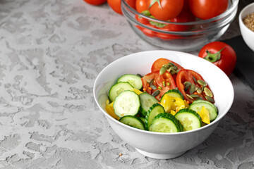 Ceramic bowl of tomato and cucumber salad on table