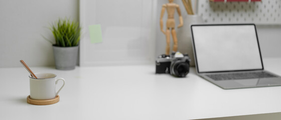 Modern home office desk with copy space, mock-up laptop, camera and decorations