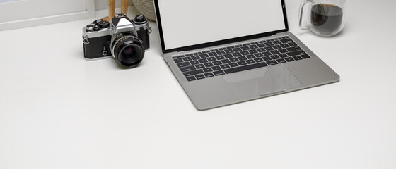 Modern worktable with copy space, mock-up laptop, camera, coffee mug and decorations