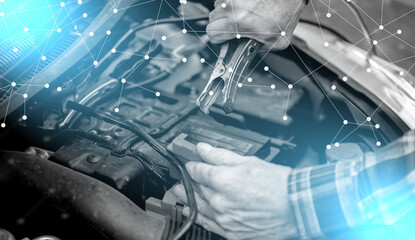Hands of car mechanic using car battery jumper cable; light effect