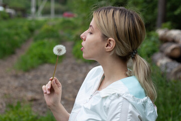 girl is blows away dandelion blowball