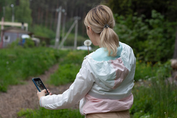 girl is blows away dandelion blowball and doing selfi on phone