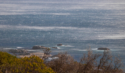 View of an extremely windy ocean with rocks in water.
