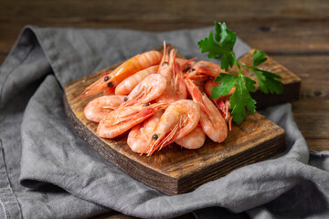 Shrimp on a wooden Board on a brown wooden table. Lots of prawns on the serving Board. Prawns close up