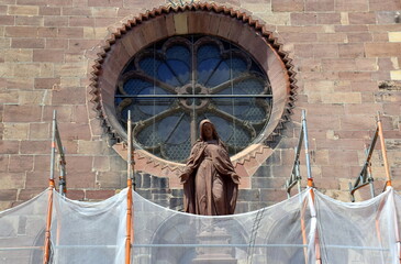 Marienfigur am Freiburger Münster hinter einem Baustellennetz