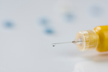 Syringe with a thin needle and some pills.