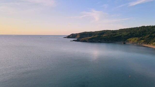Flying next to the shore above the sea, approaching green hills while the sun is rising  Sozopol, Bulgaria